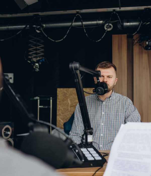 Two college podcasters laughing and having a good time in a studio. Two happy young men co-hosting a live audio broadcast.