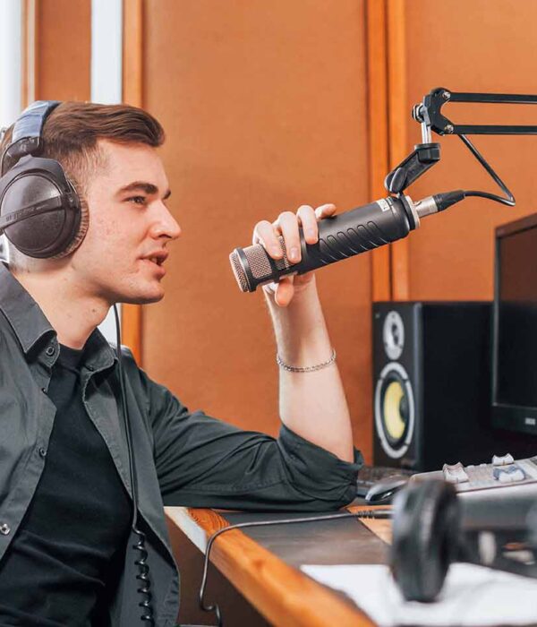 Talks and uses mic. Young man is indoors in the radio studio is busy by broadcast.
